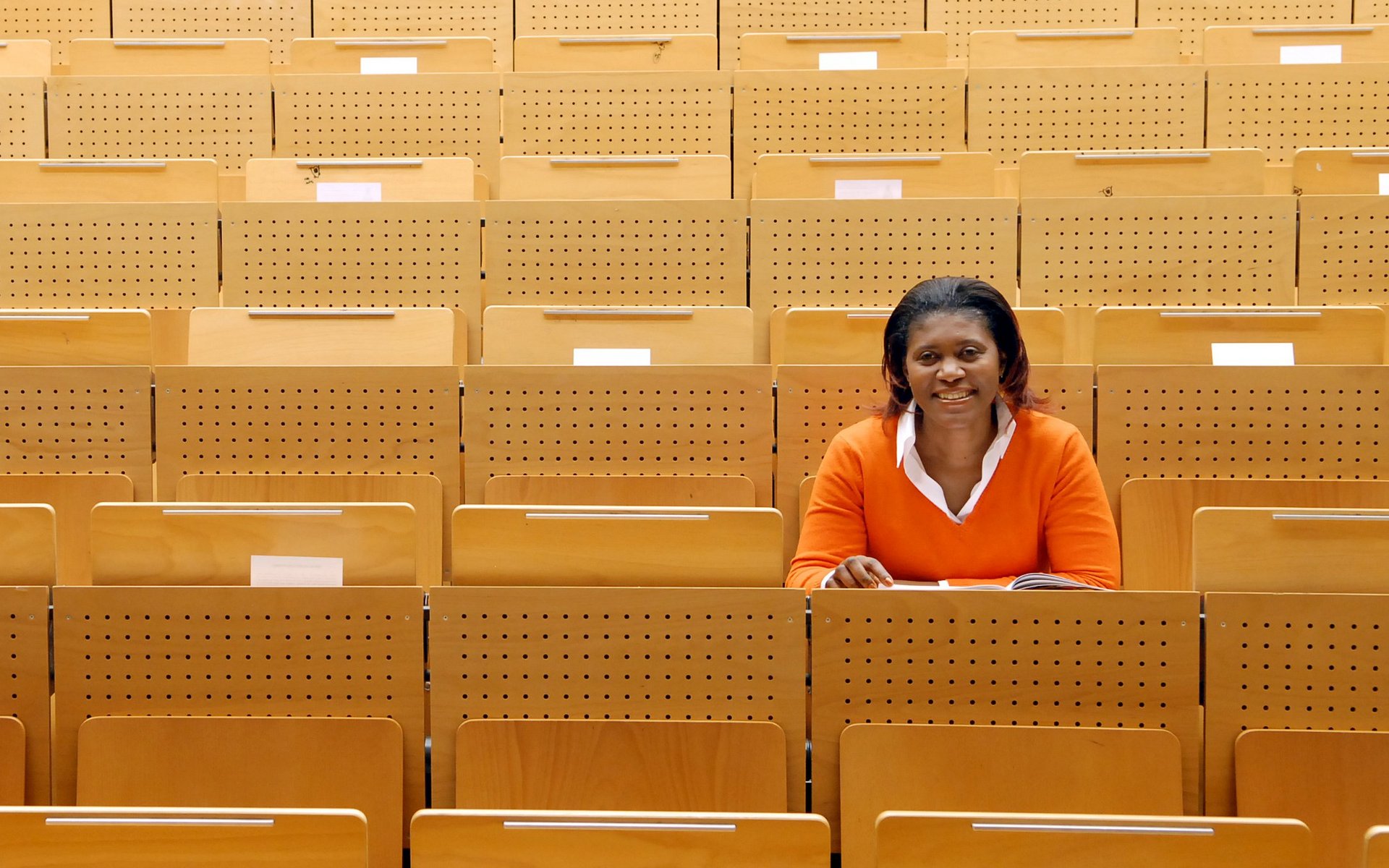Studieneignung internationaler Bewerbender – Validität von Studieneignungstests | g.a.s.t./Wiemer Eine farbige Studentin sitzt in einem leern Hörsaal und hat ihren Blick nach vorne gerichtet.