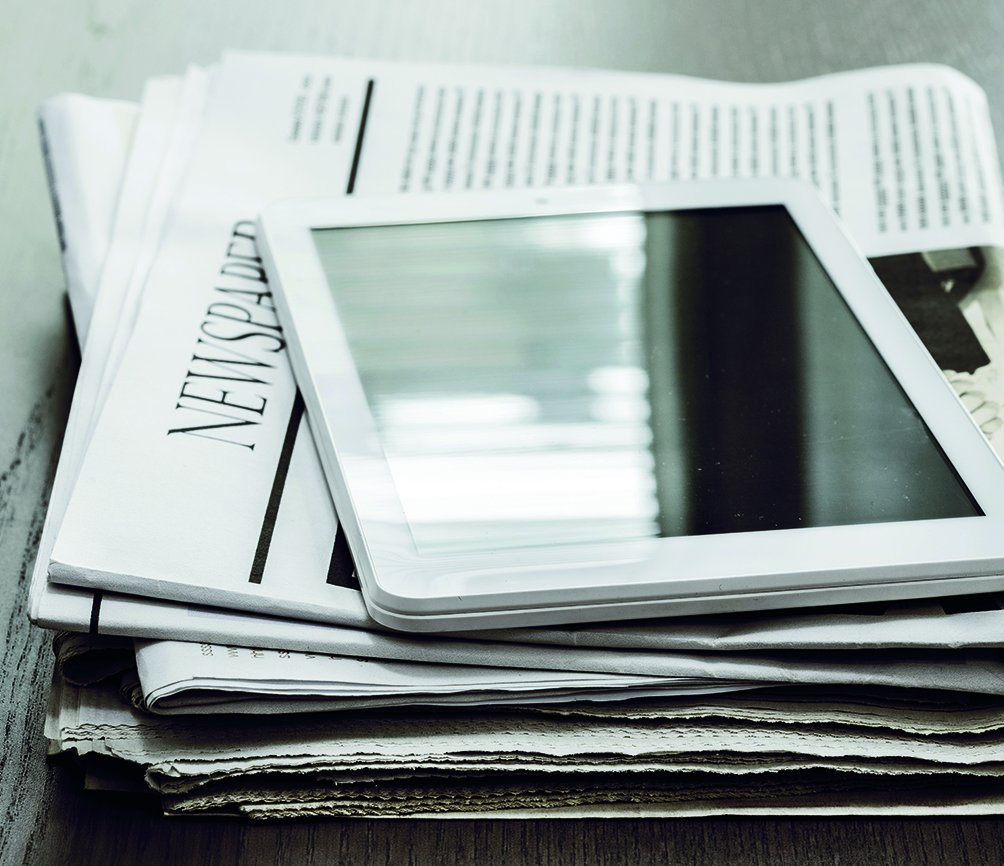 g.a.s.t.-News | AdobeStock Ein Tablett liegt auf einem Stapel Zeitungen. Hier gibt es Aktuelles von g.a.s.t.