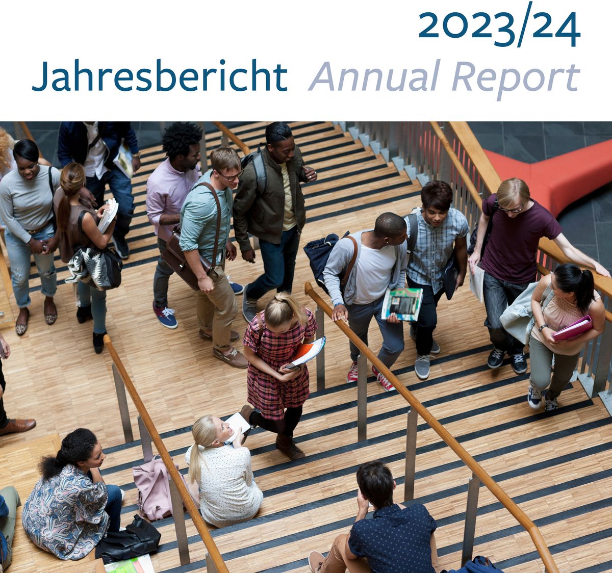 Das Titelbild des g.a.s.t.-Jahresberichts zeigt einen Blick von oben links auf eine Gruppe junger Erwachsender im Foyer eines Hörsaalgebäudes.